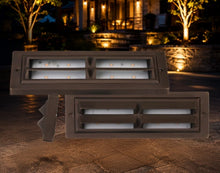 Load image into Gallery viewer, Two rectangular outdoor LED landscape light fixtures in a dark bronze finish, shown against a nighttime patio backdrop with a house and trees in the background.
